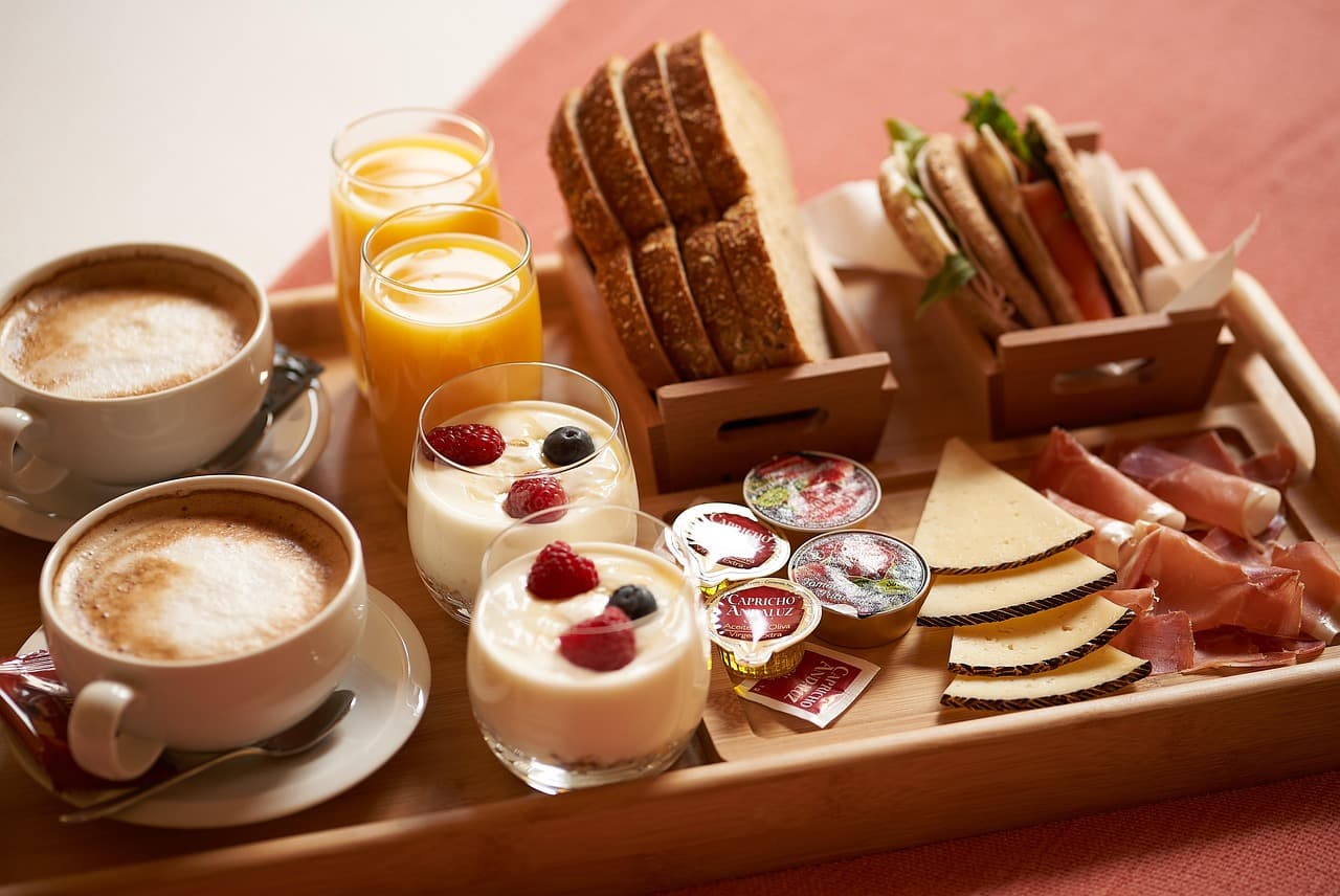 Frühstückstablett mit Brötchen, Käse, Marmelade und Kaffee